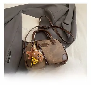 Detailed close-up of retro brown pillow bag with bear charm on grey suit background