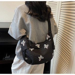 Detail of colorful butterfly embroidery on a black nylon crossbody bag with wide strap