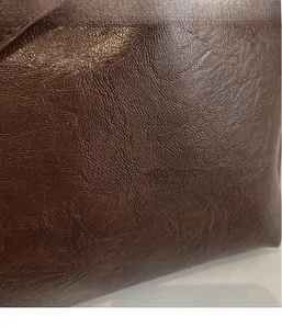 Close-up of high-quality dark brown leather texture on a vintage tote bag