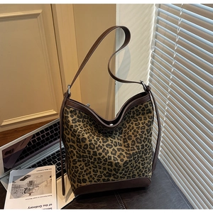 Detail of leopard print bucket bag with brown leather trim and silver metal hardware