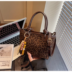 Dettaglio borsa leopardata con nappina di perline e manici in pelle marrone scuro
