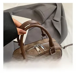 Detail of vintage brown leather handbag featuring dual handles and sturdy metal zippers