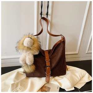 Detail of dark brown suede bucket bag with leather strap and cute lion plush charm