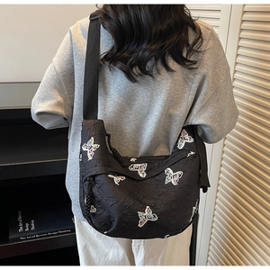 Detail of black hobo bag with colorful butterfly embroidery and wide strap for daily commute