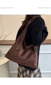 Détail du daim synthétique marron foncé et de la boucle métallique vintage du sac à bandoulière
