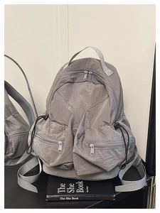 Detail view of water-resistant gray nylon backpack with multiple zipper pockets