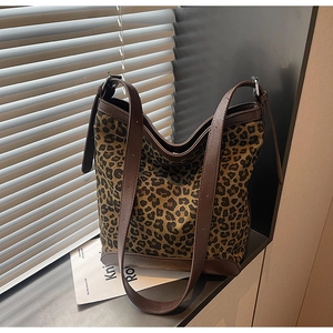 Detail of leopard print canvas bucket bag with brown leather trim and adjustable straps