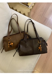 Close-up of retro brown shoulder bags with beaded charms on a white minimalist sofa