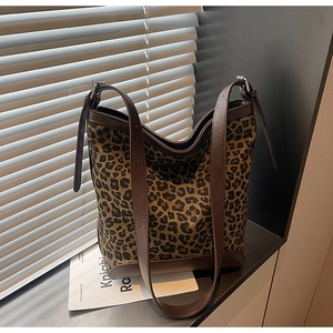 Macro shot of leopard print canvas texture and brown leather trim on a bucket bag