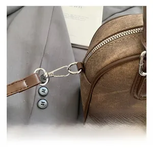 Detail showing the silver metal hook and brown leather strap on a retro pillow bag