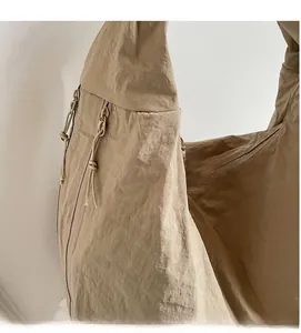 Gros plan du sac en nylon kaki montrant la texture douce du tissu et les fermetures éclair