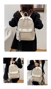 Detail view of cream white woven texture backpack with silver astronaut charm accessory