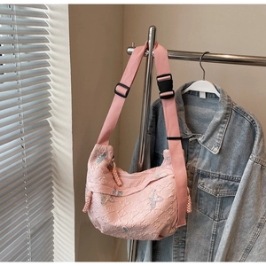 Detailed close-up of pink crescent canvas bag with butterfly embroidery and woven strap