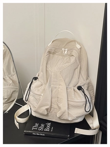 Detail of beige plaid backpack featuring black drawstring closure and durable fabric