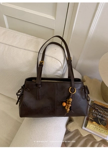 Detail of dark brown retro shoulder bag with golden zipper and decorative wood beads