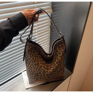 Close-up of leopard print bucket bag with dark brown leather trim and wide shoulder strap