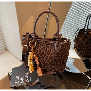 Dettaglio borsa a secchiello leopardata con finiture in pelle marrone e perline in legno