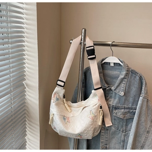 Detail of white moon bag featuring butterfly embroidery and adjustable wide strap
