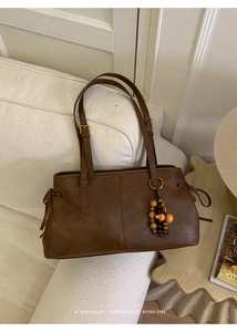 Detail of retro brown leather shoulder bag featuring decorative multi-color wooden beads