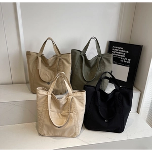 Detail showing canvas tote bags in khaki, olive, and cream with metal buckle pocket