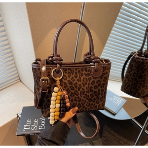 Dettaglio della borsa a secchiello leopardata con finiture in pelle e perle di legno