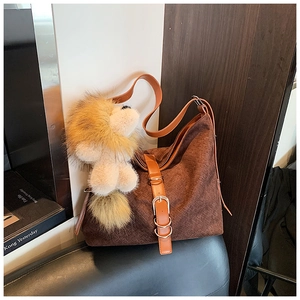 Close-up of brown suede bucket bag with woven texture and lion fur pendant