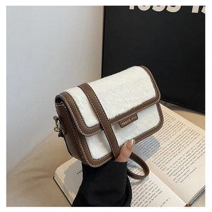 Détail du sac bandoulière rétro bicolore avec fourrure blanche et finitions en cuir brun