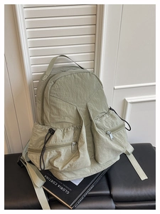Close-up of light green multi-pocket backpack with nylon texture on a leather bench