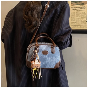Blue denim Boston bag with brown leather trim and bear charm shown in a crossbody style