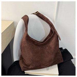 Détail du sac fourre-tout en daim marron foncé avec boucle de réglage dorée sur la bandoulière