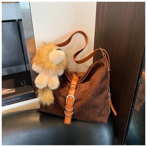 Detail of dark brown hobo tote bag featuring a cute lion plush charm on leather strap