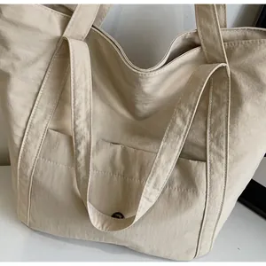 Detail view of the beige tote bag with a front pocket and durable textured nylon fabric
