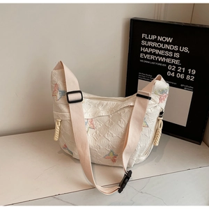 Close-up of white quilted canvas dumpling bag with colorful butterfly embroidery details