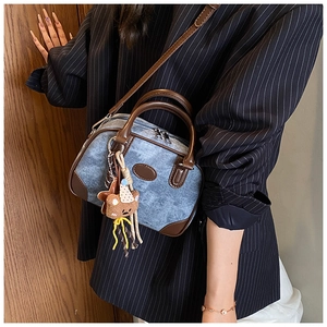 Close-up of denim and leather stitching on a retro bag with a cute bear plush charm