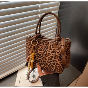 Dettaglio borsa a secchiello leopardata con nappa in legno e tracolla rimovibile