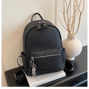 Detailed close-up of the black woven leather texture and silver bear charm on the backpack
