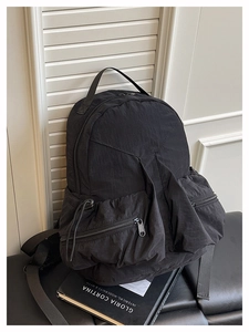 Detail of multi-pocket black nylon outdoor backpack with side drawstring on leather seat