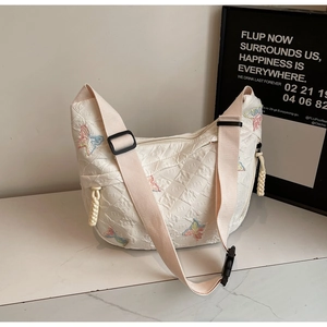 Detail of white quilted canvas bag featuring colorful butterfly embroidery and wide strap