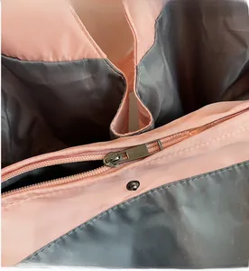 Détail de la fermeture éclair rose fluide et du bouton-pression en métal du sac cabas