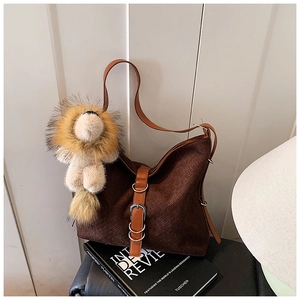 Detail of dark brown woven shoulder bag with leather strap and lion plush charm decoration