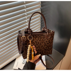 Dettaglio della borsa a secchiello leopardata con texture scamosciata e ciondolo di perline