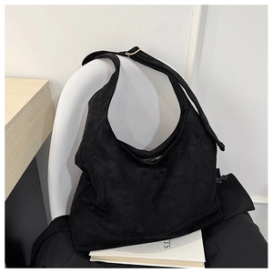 Détail de la boucle dorée réglable et de la bandoulière en daim noir sur un sac fourre-tout