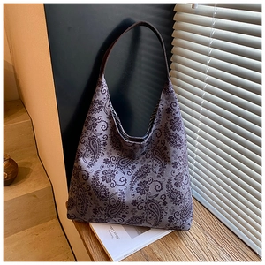 Detail of purple paisley canvas tote bag featuring brown leather shoulder strap texture