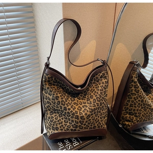 Detail of leopard print bucket bag with brown leather trim and adjustable shoulder strap