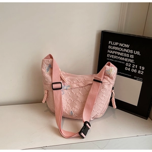 Detail of pink quilted crescent bag featuring colorful butterfly embroidery and wide strap