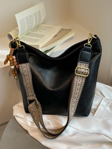 Black soft leather bucket bag with jacquard strap and wooden beads on white fabric