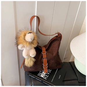 Close-up of brown woven hobo bag with leather strap and cute lion plush charm detail
