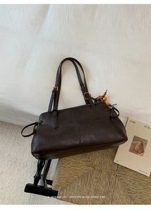 Detailed macro view of retro brown leather tote with a unique wooden bead pendant accessory