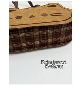 Detail view of the cat-themed handbag featuring a thickened bottom and brown plaid fabric