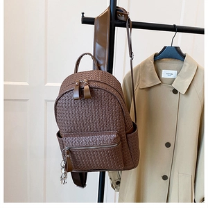 Detailed view of brown woven PU leather backpack with silver zippers and side pockets